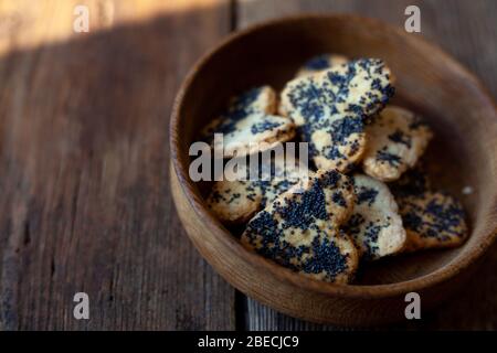 Hausgemachte Kekse mit Mohnsamen in einem Holzteller auf einem Holzhintergrund. Hausgemachte Speisen. Stockfoto