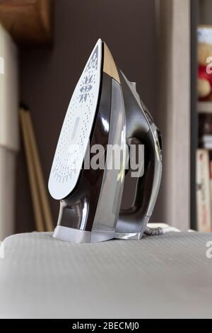 Ein Porträt eines stehenden flatiron oder einfach nur auf einem Bügelbrett in einem Wohnzimmer, bereit, um Kleidung und andere Stücke von Stoff so th Bügeln verwendet werden Stockfoto