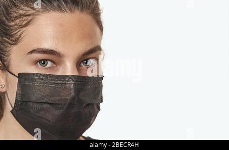 Ein Nahaufnahme-Porträt einer hübschen Frau mit Stethoskop, die eine auf weißem Hintergrund isolierte chirurgische Maske trägt. Stockfoto