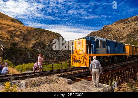 Touristen beobachten die Pukerangi Zug von DJ3211 überqueren Sie die Tiefe Stream Viadukt über die Dunedin Eisenbahn, ehemalige Taieri Gorge Railway geschleppt. Otago, Stockfoto