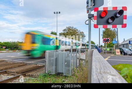 Schnell. Klasse 377 Electrostar Southern Rail Zug mit Motion Blur über einen Bahnübergang im Süden Großbritanniens zu bewegen. Southern Train. Stockfoto