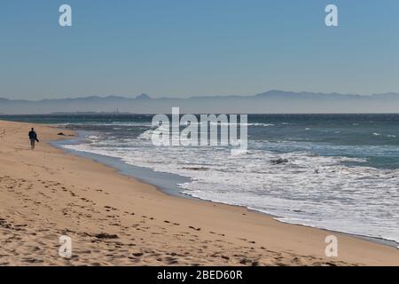 Tarifa, Spanien. Februar 2020. Mann, der alleine am Bolonia Strand in der Nähe von Tarifa mit afrikanischen Bergen im Hintergrund läuft Stockfoto