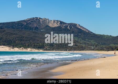 Tarifa, Spanien. Februar 2020. Mann, der alleine am Bolonia Strand in der Nähe von Tarifa mit afrikanischen Bergen im Hintergrund läuft Stockfoto