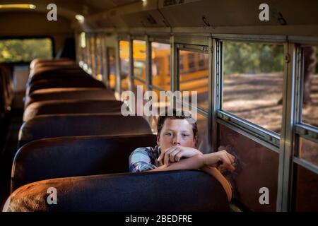 Porträt eines Teenagers, der in einem leeren Schulbus sitzt Stockfoto