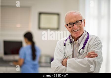 Porträt eines lächelnden Oberarztes, der mit gefalteten Armen steht. Stockfoto