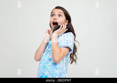 Teenager-Mädchen kommuniziert emotional auf dem Telefon auf einem weißen Studio Hintergrund. Stockfoto