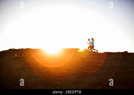 Zwei junge Frauen laufen zusammen bei Sonnenuntergang Stockfoto