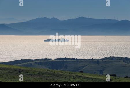 Frachtschiff, das die Straße von Gibraltar von Andalusien aus mit den marokkanischen Bergen im Hintergrund überquert Stockfoto