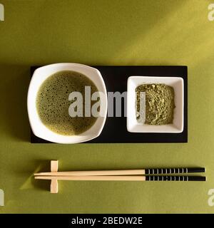 Pulver und Matcha Tee auf grünem Hintergrund Stockfoto