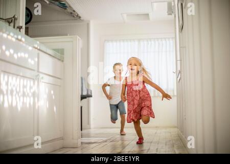 Zwei kleine Mädchen haben Spaß beim gemeinsamen Durchlaufen des Hauses Stockfoto