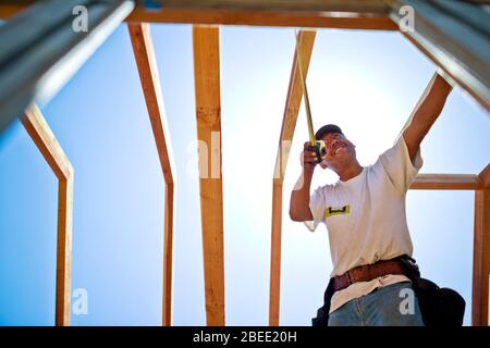 Zimmermann mittleren Alters, der an der Holzkonstruktion eines Gebäudes arbeitet Stockfoto