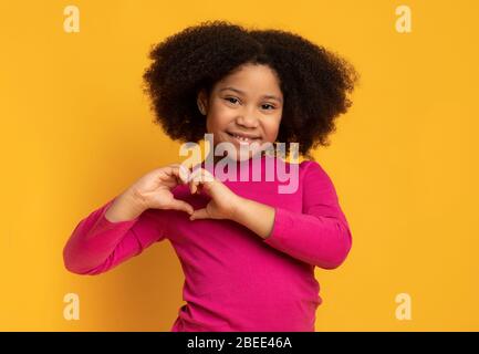 Nettes kleines afroamerikanisches Mädchen, das Herzform mit ihren Händen macht Stockfoto