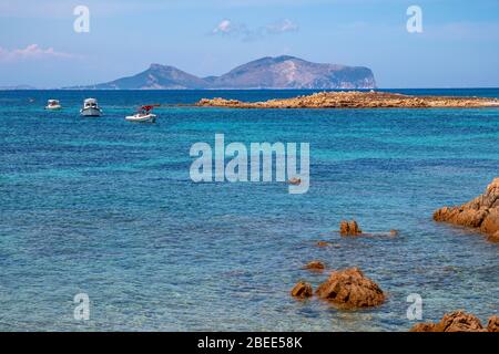 Tavolara, Sardinien / Italien - 2019/07/18: Tyrrhenisches Meer mit Yachten vor der Küste Isola Tavolara mit Capo Figari Kap, Monte Ruju Gipfel Stockfoto