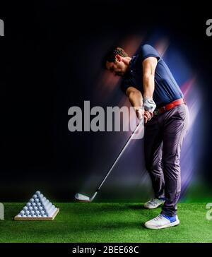 Golfspieler, der in einer Driving Range mit Pyramide von Golfbällen praktiziert Stockfoto