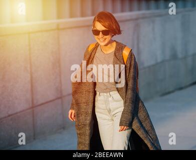 Junge glückliche kurzhaarige Brünette Frau ist Skateboard in einer Stadt reiten. Stockfoto