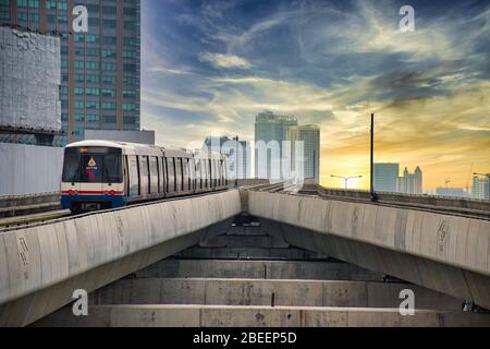 Bangkok, Thailand 04.11.2020: Skytrain verlässt die Ratchayothin BTS Station auf der Sukhumvit Line in Richtung blau-gelber Sonnenuntergang Stockfoto