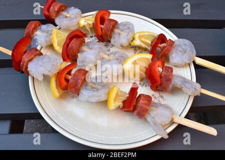 Rohe saftige Garnelen-Spieße mit Zitrone und rotem Pfeffer, bereit, auf den Holzkohlegrill geworfen zu werden. Meeresfrüchte machen Gourmet-Kebabs und ist schnell zu kochen. Stockfoto