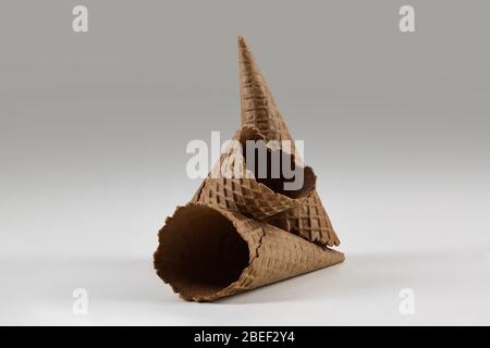 Drei leere, leckere, braune Waffelzapfen für Eis auf weiß isoliert. Konzept der Lebensmittel, Leckereien. Mockup, Vorlage für Werbung und Design. Nahaufnahme Stockfoto