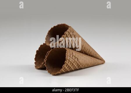 Drei leere, braune Wafer-Zapfen für Eis auf weiß isoliert. Konzept der Lebensmittel, Leckereien. Mockup, Vorlage für Werbung und Design. Nahaufnahme Stockfoto