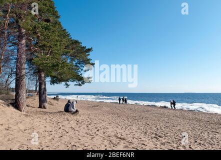 Komarovo, Sankt Petersburg, Russland – 22. März 2020: Die Menschen entspannen sich am Sandstrand des Finnischen Meerbusens in der Gemeinde Komarovo Stockfoto