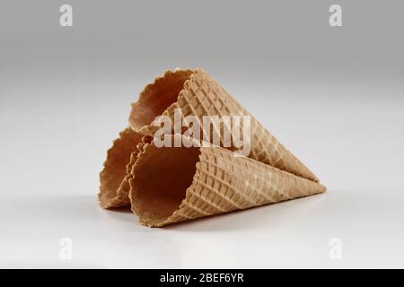 Drei leere, knusprige Wafer-Zapfen für Eis auf weiß isoliert. Konzept der Lebensmittel, Leckereien. Mockup, Vorlage für Ihre Werbung und Design. Nahaufnahme Stockfoto