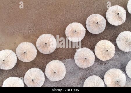 Luftaufnahme der Wellen, Sandstrand mit Schilfschirmen Stockfoto