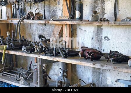 Verrostete alte Werkzeuge und Anlagenteile in den Regalen im Wartungsraum Stockfoto