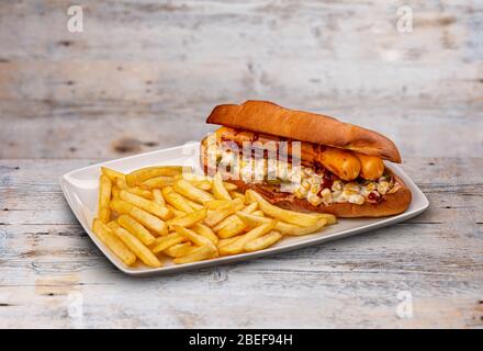 Gegrillter würziger Bratwurstburger und pommes frites auf Holztisch Stockfoto