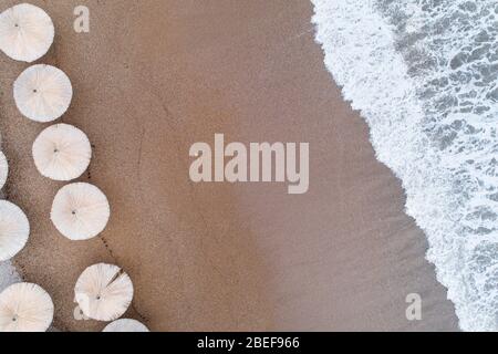 Luftaufnahme der Wellen, Sandstrand mit Schilfschirmen Stockfoto