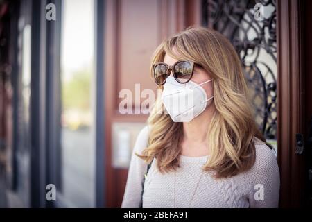 Nahaufnahme einer Frau mittleren Alters, die auf der Straße steht und eine Atemschutzmaske zum Schutz der Gesundheit trägt und sich schnell über das Coronavirus ausbreitet Stockfoto