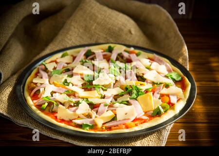 Rohe Pizza mit sortierter Füllung in Metallform Stockfoto