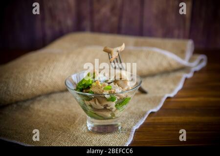 Eingelegter Pilzsalat mit Salat, Zwiebeln und Kräutern in einer Glasschüssel Stockfoto