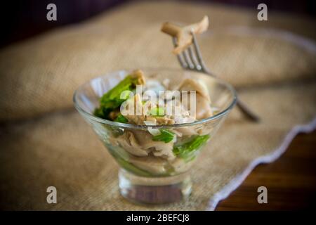 Eingelegter Pilzsalat mit Salat, Zwiebeln und Kräutern in einer Glasschüssel Stockfoto