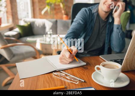 Kreativer Arbeitsplatz - organisierter Arbeitsplatz, wie Sie ihn zur Inspiration mögen. Mann, der im Büro in bequemer Kleidung, entspannter Position und unordentlichem Tisch arbeitet. Wählen Sie die gewünschte Atmosphäre - ideal klar oder Chaos. Stockfoto