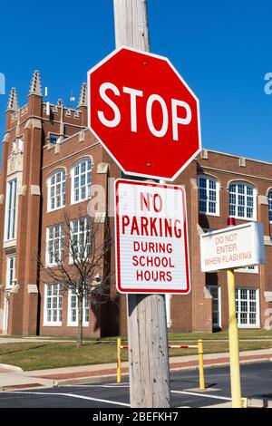 Kein Parkplatz während der Schulzeit und Stoppschild mit Schulgebäude im Hintergrund. Stockfoto