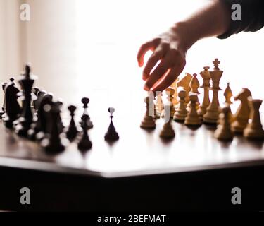 Während der 2020-Pandemie des Coronavirus in Quarantäne und Selbstisolierung verweilend, spielen Vater und Sohn ein Schachspiel, um die Zeit gemeinsam zu verbringen. Stockfoto
