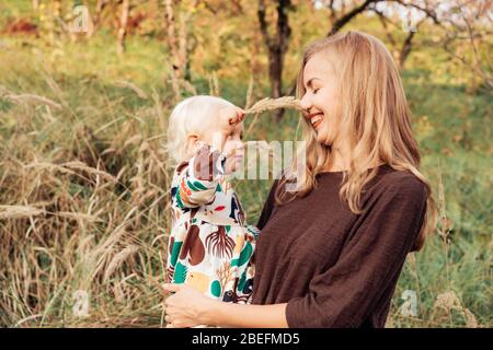 Mutter hält eine kleine charmante Tochter in den Armen. Umarmt sanft. Stockfoto