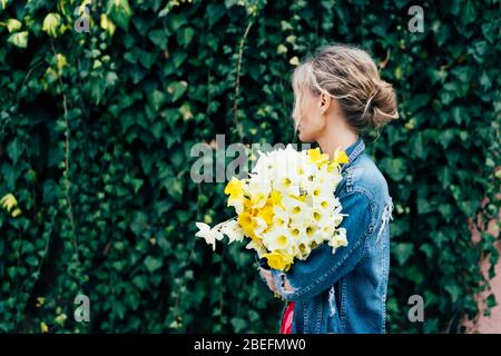 Frühlingsinhalt. Junge charmante blonde Hipster mit einem Bouquet von Narzissen Stockfoto