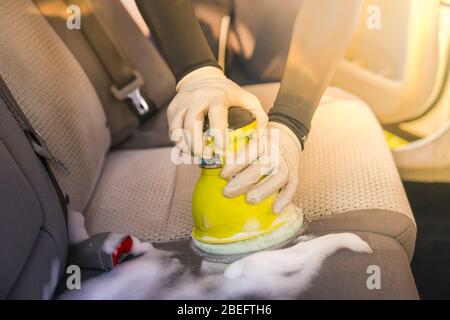 Ein Mann Reinigung Innenraum durch Schaum chemische und schrubben. Stockfoto