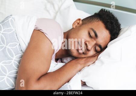 Bild von einem erholsamen Schlaf jungen afrikanischen Kerl am Morgen im Schlafzimmer liegt im Bett. Stockfoto