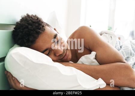 Bild von einem erholsamen Schlaf jungen afrikanischen Kerl am Morgen im Schlafzimmer liegt im Bett. Stockfoto