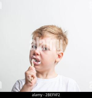 Niedlicher Junge posiert mit Bambus Zahnbürste in seinem Mund, Kind bürstet seine Zähne Stockfoto