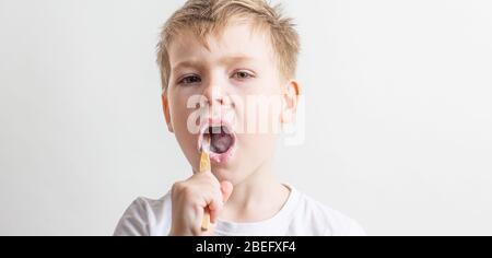 Niedlicher Junge posiert mit Bambus Zahnbürste in seinem Mund, Kind bürstet seine Zähne Stockfoto