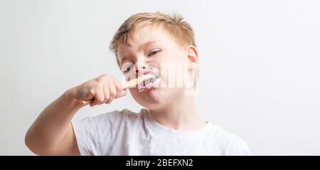 Niedlicher Junge posiert mit Bambus Zahnbürste in seinem Mund, Kind bürstet seine Zähne Stockfoto