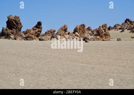 Etwas Sand, vulkanische Felsen im Hintergrund Stockfoto