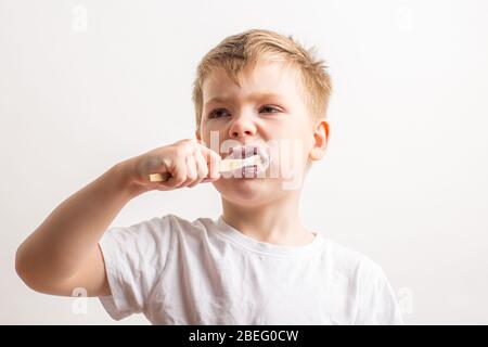 Niedlicher Junge posiert mit Bambus Zahnbürste in seinem Mund, Kind bürstet seine Zähne Stockfoto