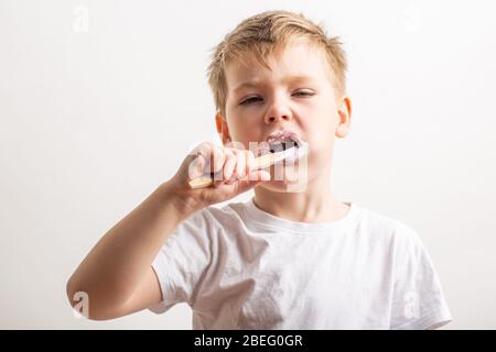 Niedlicher Junge posiert mit Bambus Zahnbürste in seinem Mund, Kind bürstet seine Zähne Stockfoto