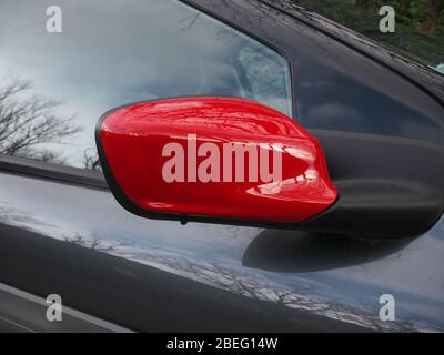 Roter Seitenspiegel hinten. Rechte Seite. Bäume spiegeln sich am Fenster Stockfoto
