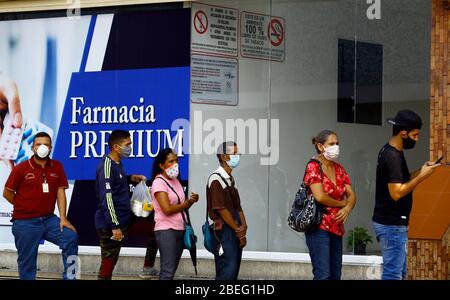 Guacara, Carabobo, Venezuela. April 2020. 13. April 2020. Die Leute stehen am Eingang einer Apotheke an, um Medikamente zu kaufen. Durch vorbeugende Maßnahmen gegen das Coronavirus können bis zu 5 Personen in das Gebäude eindringen und Alkohol wird versprüht, um das mögliche Vorhandensein des Virus zu beseitigen. In Guacara, Bundesstaat Carabobo. Foto: Juan Carlos Hernandez Quelle: Juan Carlos Hernandez/ZUMA Wire/Alamy Live News Stockfoto