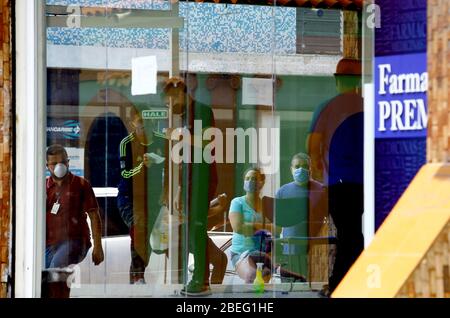 Guacara, Carabobo, Venezuela. April 2020. 13. April 2020. Die Leute stehen am Eingang einer Apotheke an, um Medikamente zu kaufen. Durch vorbeugende Maßnahmen gegen das Coronavirus können bis zu 5 Personen in das Gebäude eindringen und Alkohol wird versprüht, um das mögliche Vorhandensein des Virus zu beseitigen. In Guacara, Bundesstaat Carabobo. Foto: Juan Carlos Hernandez Quelle: Juan Carlos Hernandez/ZUMA Wire/Alamy Live News Stockfoto